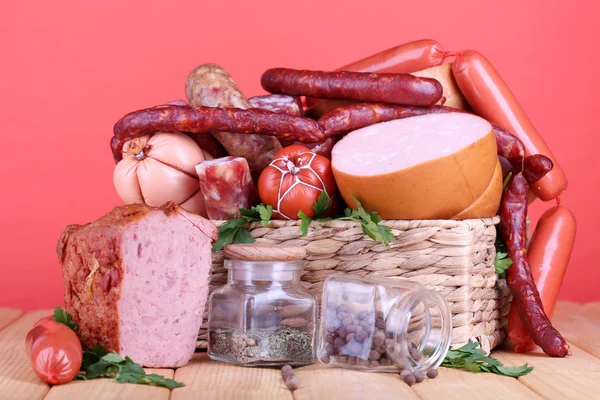 Lote de salsichas diferentes na mesa de madeira no fundo vermelho — Fotografia de Stock