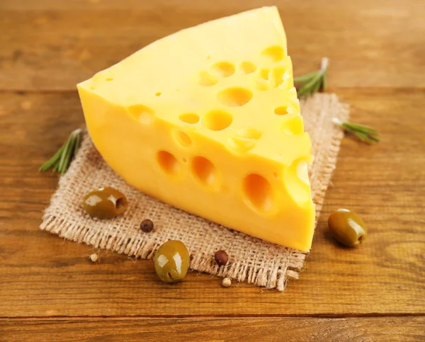 Stuk kaas met groene olijven, op houten achtergrond — Stockfoto