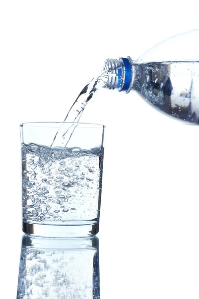 Pour water from bottle into  glass, on light blue background — Stock Photo, Image