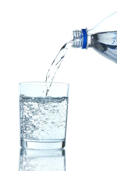 Вылейте воду из бутылки в стекло, на светло-голубом фоне — стоковое фото