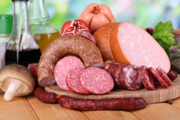 Different sausages on wooden table on natural background — Stock Photo, Image