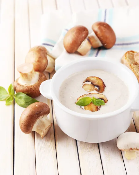 Mushroom soup in white pot, on napkin, on wooden background — Stock Photo, Image