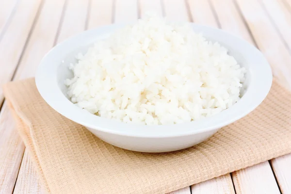 Vařená rýže v misce na dřevěné pozadí — Stock fotografie