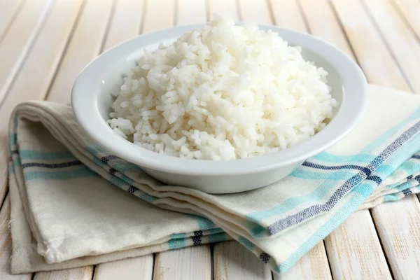 Vařená rýže v misce na dřevěné pozadí — Stock fotografie