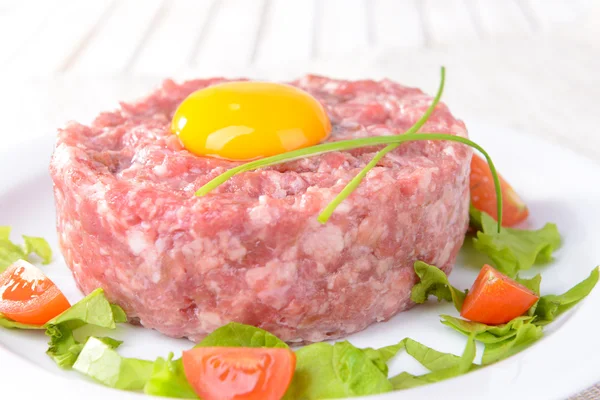 Delicioso bife tartare com gema de ovo na placa na mesa close-up — Fotografia de Stock