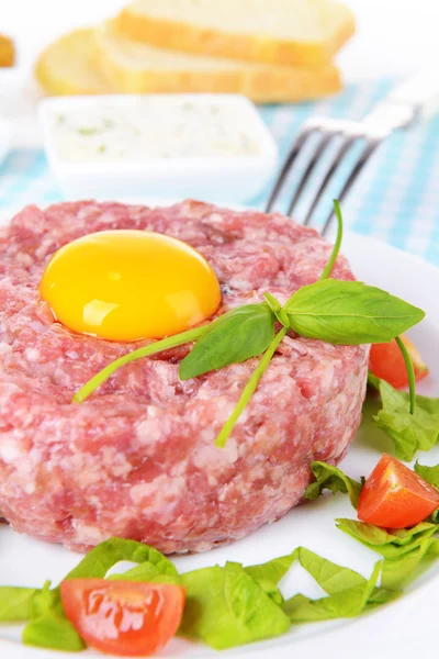 Delicious steak tartare with yolk on plate on table close-up — Stock Photo, Image