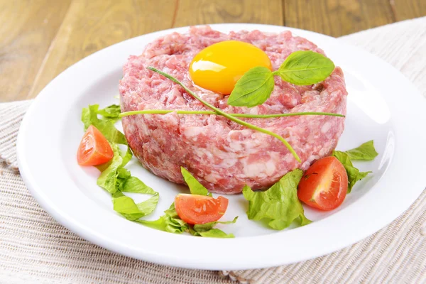 Delicious steak tartare with yolk on plate on table close-up — Stock Photo, Image