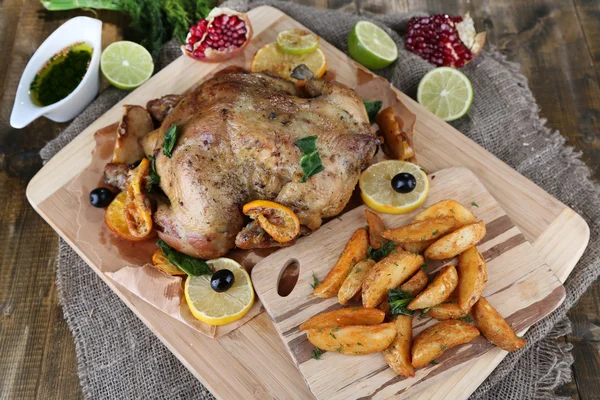 Poulet rôti entier aux légumes et pommes de terre frites sur planche de bois, sur fond de bois — Photo