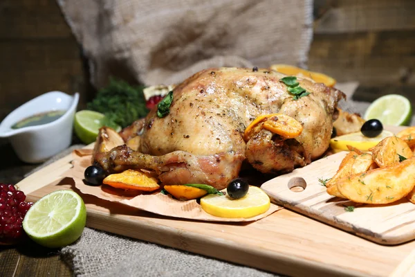 Ahşap masa, ahşap zemin üzerine kızarmış patates ve sebze ile bütün kavrulmuş tavuk — Stok fotoğraf