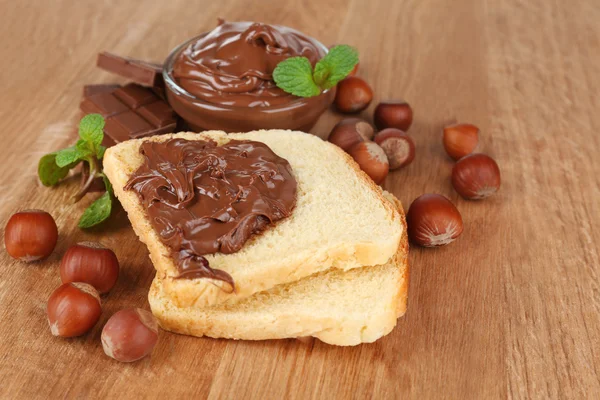 Ψωμί με γλυκιά σοκολάτα φουντούκι εξαπλωθεί σε ξύλινα φόντο — Φωτογραφία Αρχείου