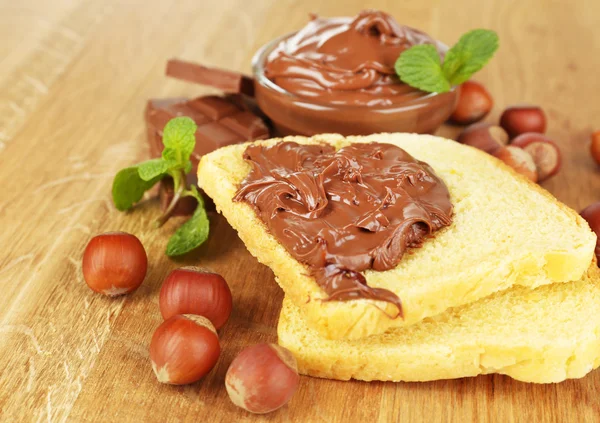 Bread with sweet chocolate hazelnut spread on wooden background — Stock Photo, Image