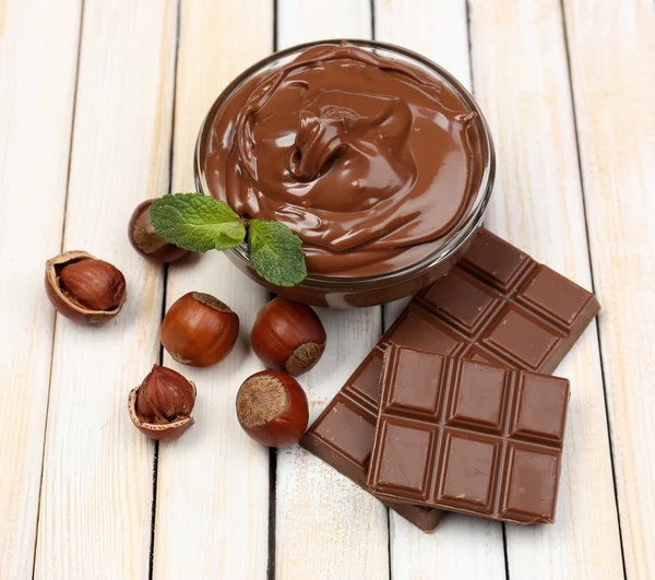 Sweet chocolate hazelnut spread with whole nuts and mint on wooden background — Stock Photo, Image