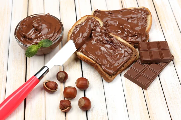 Bröd med söt choklad hasselnöt sprida på trä bakgrund — Stockfoto