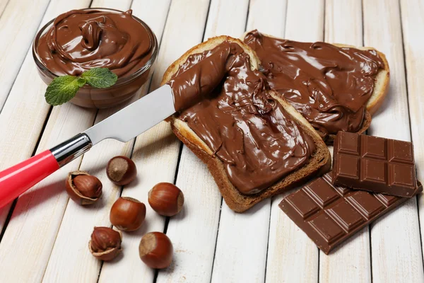 Brood met zoete chocolade hazelnoot verspreid over houten achtergrond — Stockfoto