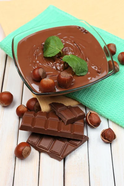 Süßer Schokoladen-Haselnussaufstrich mit ganzen Nüssen und Minze auf Holzgrund — Stockfoto