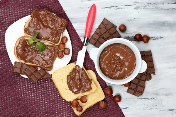 Sweet chocolate hazelnut spread with whole nuts and mint on wooden background — Stock Photo, Image