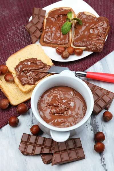 Édes csokoládé mogyoró elterjedt egész dióval és menta fából készült háttér — Stock Fotó