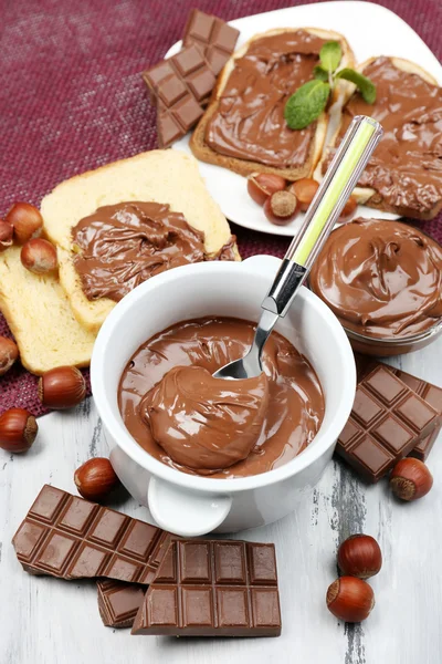 Сладкий шоколад фундук распространяется с целыми орехами и мятой на деревянном фоне — стоковое фото