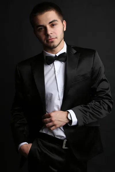 Handsome young man in suit on dark background — Stock Photo, Image