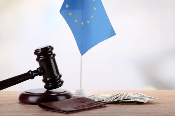Молоток, деньги, паспорт и флаг Европы, на деревянном столе, на светлом фоне — стоковое фото
