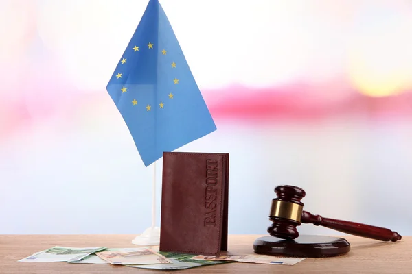 Martillo, dinero, pasaporte y bandera de Europa, sobre mesa de madera, sobre fondo claro — Foto de Stock