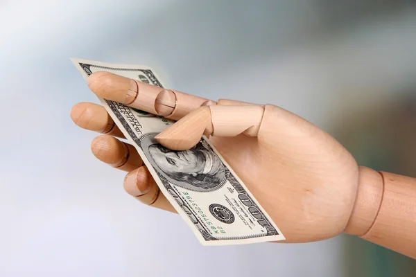 Dinero en mano de madera, sobre fondo claro — Foto de Stock