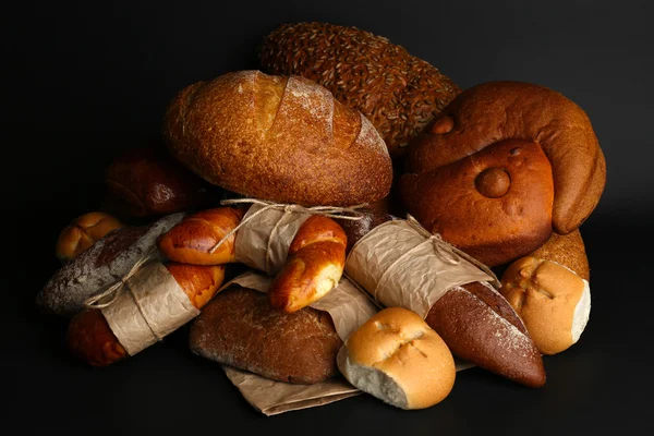 Diferentes tipos de pão no fundo preto, close-up — Fotografia de Stock