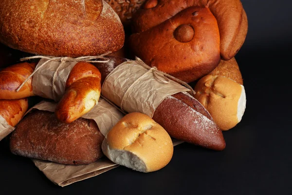 Diferentes tipos de pão no fundo preto, close-up — Fotografia de Stock