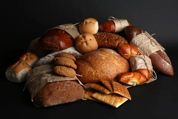Diferentes tipos de pão no fundo preto, close-up — Fotografia de Stock