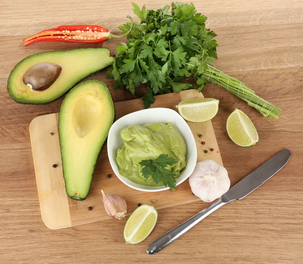 Fresh guacamole in bowl on wooden table — Stock Photo, Image