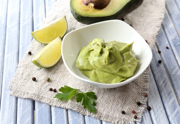 Fresh guacamole in bowl on wooden table — Stock Photo, Image