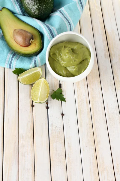 Fresh guacamole in bowl on wooden table — Stock Photo, Image