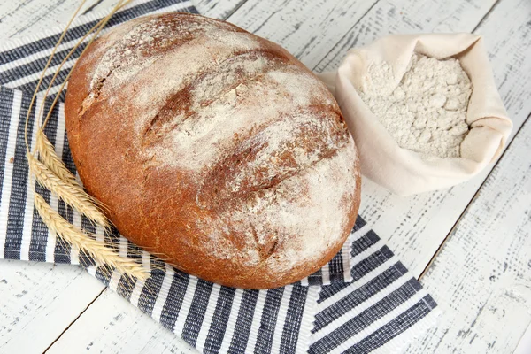 Rye bread with flour on napkin on wooden background — Stock Photo, Image