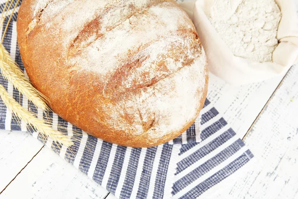 Pão de centeio com farinha em guardanapo em fundo de madeira — Fotografia de Stock