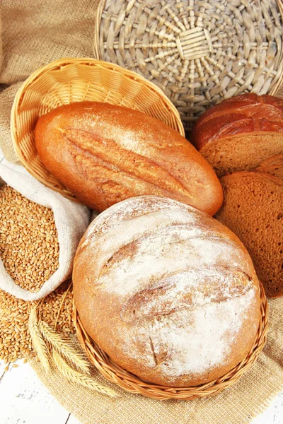 Pan de centeno con granos en la mesa sobre fondo de saco — Foto de Stock