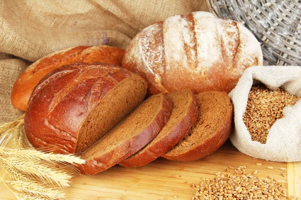 Pan de centeno con granos en la mesa sobre fondo de saco — Foto de Stock