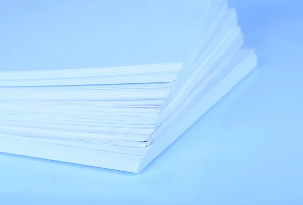 Stack white paper close-up in blue light — Stock Photo, Image