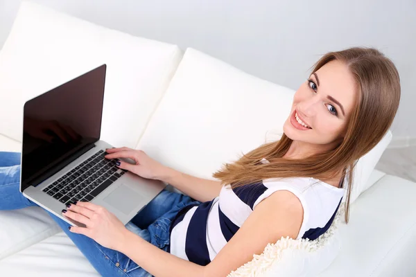 Junge Frau ruht mit Laptop auf Sofa zu Hause — Stockfoto