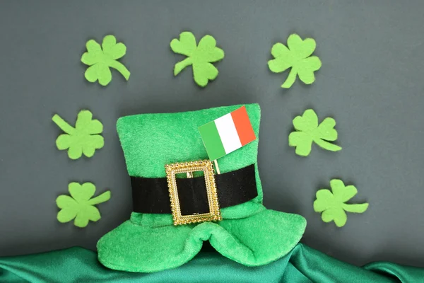 聖パトリックの日帽子とクローバーの葉と灰色の背景上のアイルランドの旗 — ストック写真