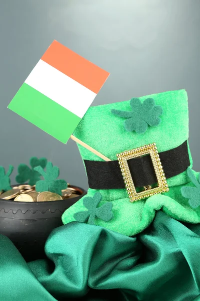 Chapéu de dia de São Patrício, pote de moedas de ouro e bandeira irlandesa sobre fundo cinzento — Fotografia de Stock