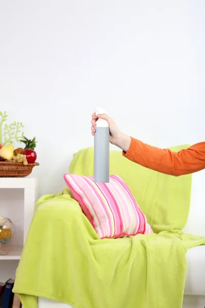 Sprayed air freshener in hand on home interior background — Stock Photo, Image