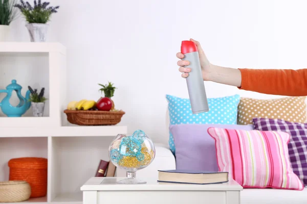 Sprayed air freshener in hand on home interior background — Stock Photo, Image