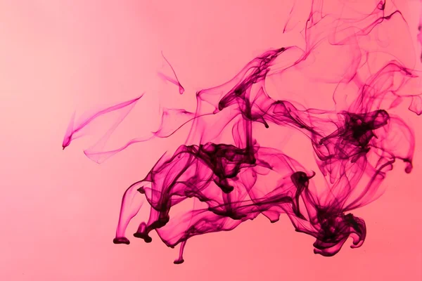 Чернила в воде на розовом фоне — стоковое фото