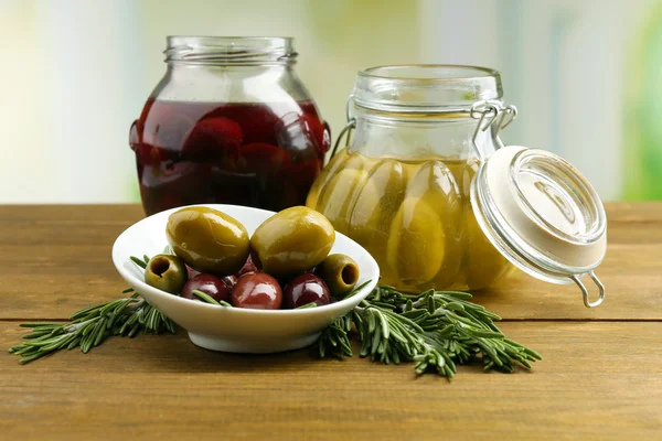 Smakelijke olijven op houten tafel, op natuurlijke achtergrond — Stockfoto