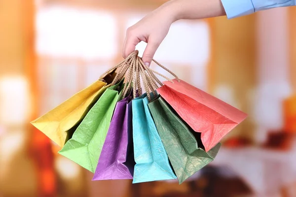 Junge Frau mit bunten Einkaufstaschen in der Hand, auf hellem Hintergrund — Stockfoto