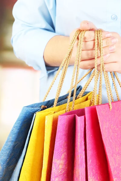 Young woman holding colorful shopping bags in  her hand, on bright background — Stock Photo, Image