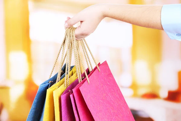 Junge Frau mit bunten Einkaufstaschen in der Hand, auf hellem Hintergrund — Stockfoto