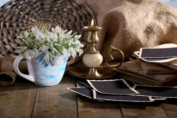 Composición con hermosas gotas de nieve en jarrón, vela, letras antiguas y fotos en mesa de madera sobre fondo de saco —  Fotos de Stock