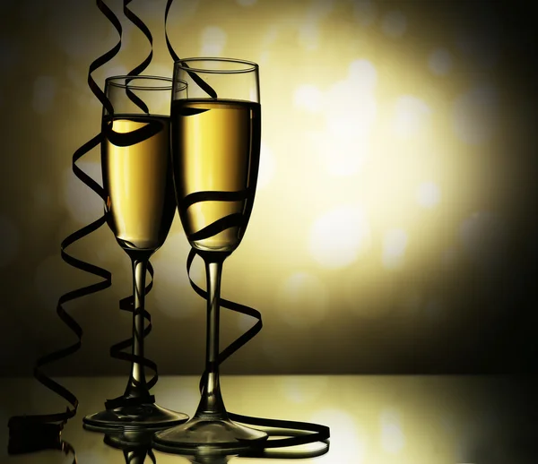 Glasses of champagne with serpentine on light background — Stock Photo, Image