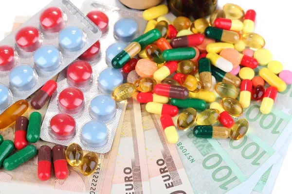 Prescription drugs on money background representing rising health care costs. Close-up — Stock Photo, Image